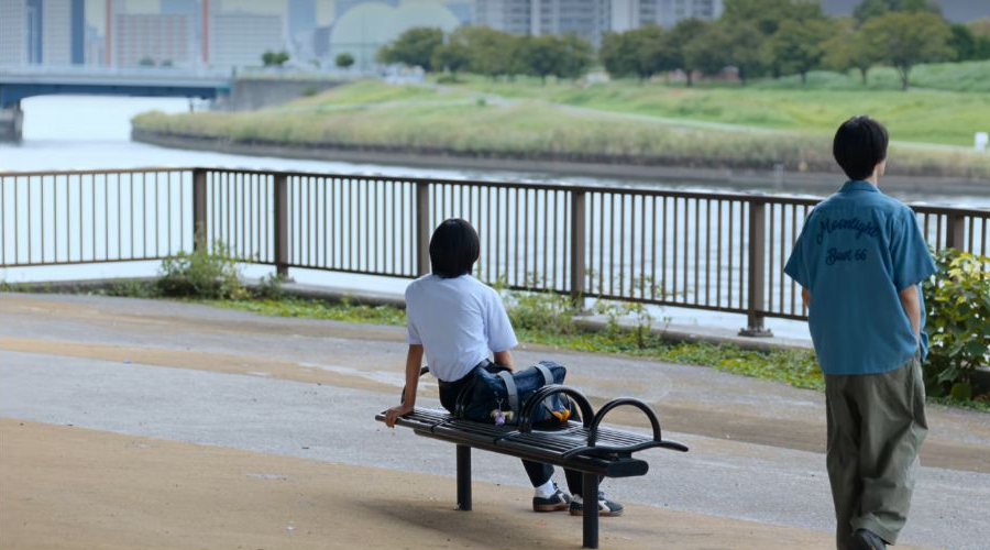 『ダウンタイム』第3話、青いシャツ姿で川沿いに立つ萩原利久さんの後ろ姿。背中に濃い色の文字が二段に入っている