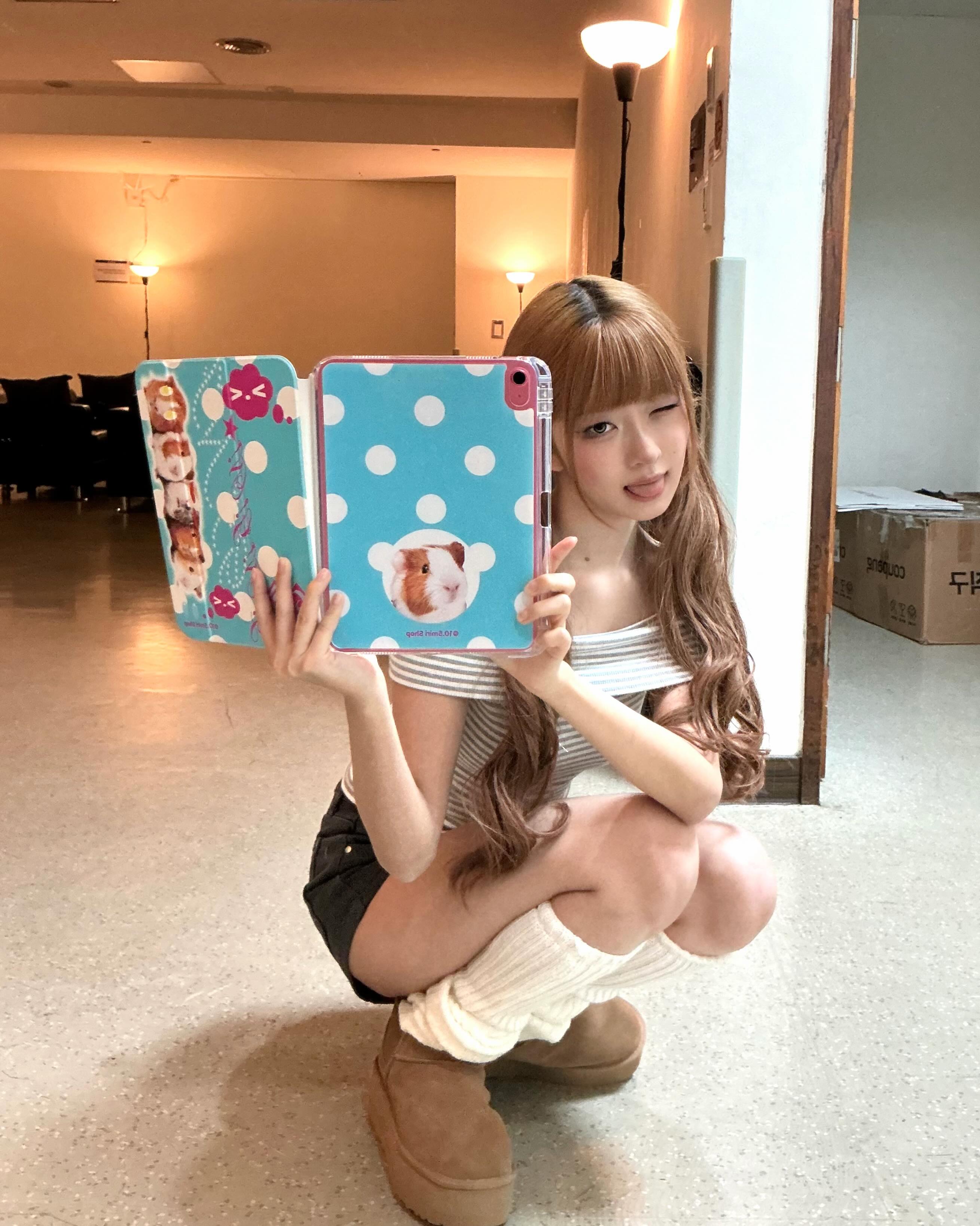 ボーダーのトップスと黒ショートパンツで鏡の前にしゃがむIVE・REIさん