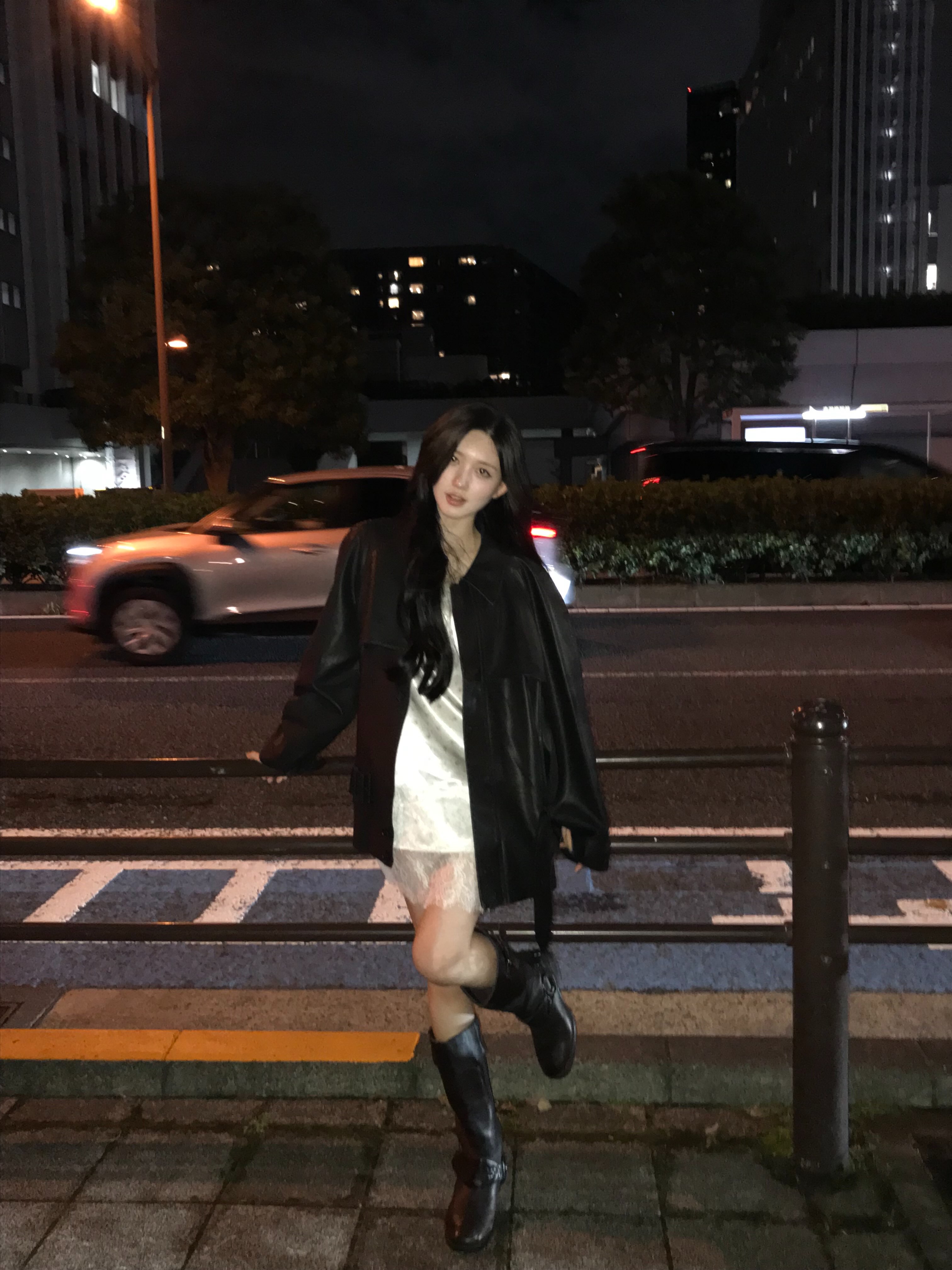 日本の夜の街で黒いレザー調ジャケットと淡い色のミニワンピースを着たガウルさん